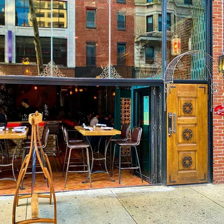 Restaurant exterior with reflective windows, ornate door, and interior glimpse.