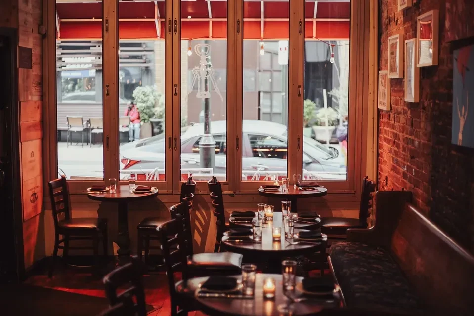 Restaurant dining room with warm light, set tables, and exposed brick.