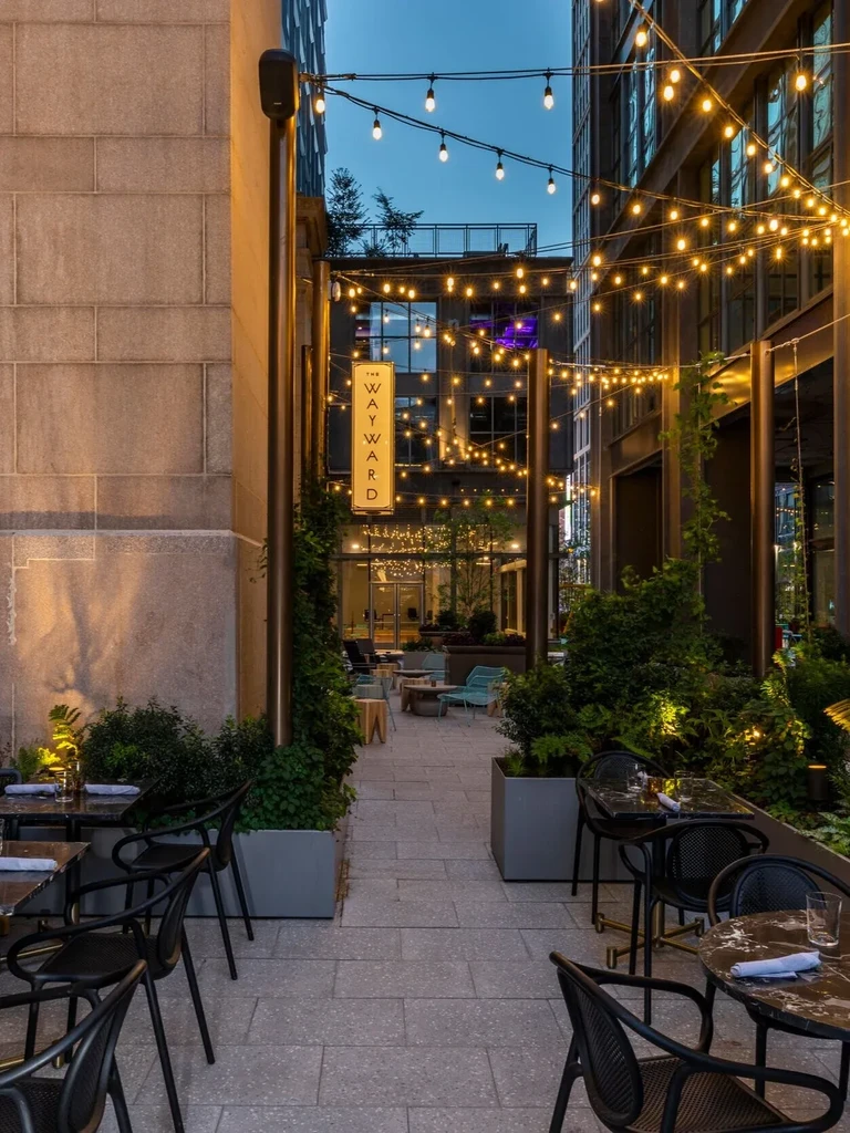Empty outdoor patio of The Wayward restaurant, lit by Edison bulbs.