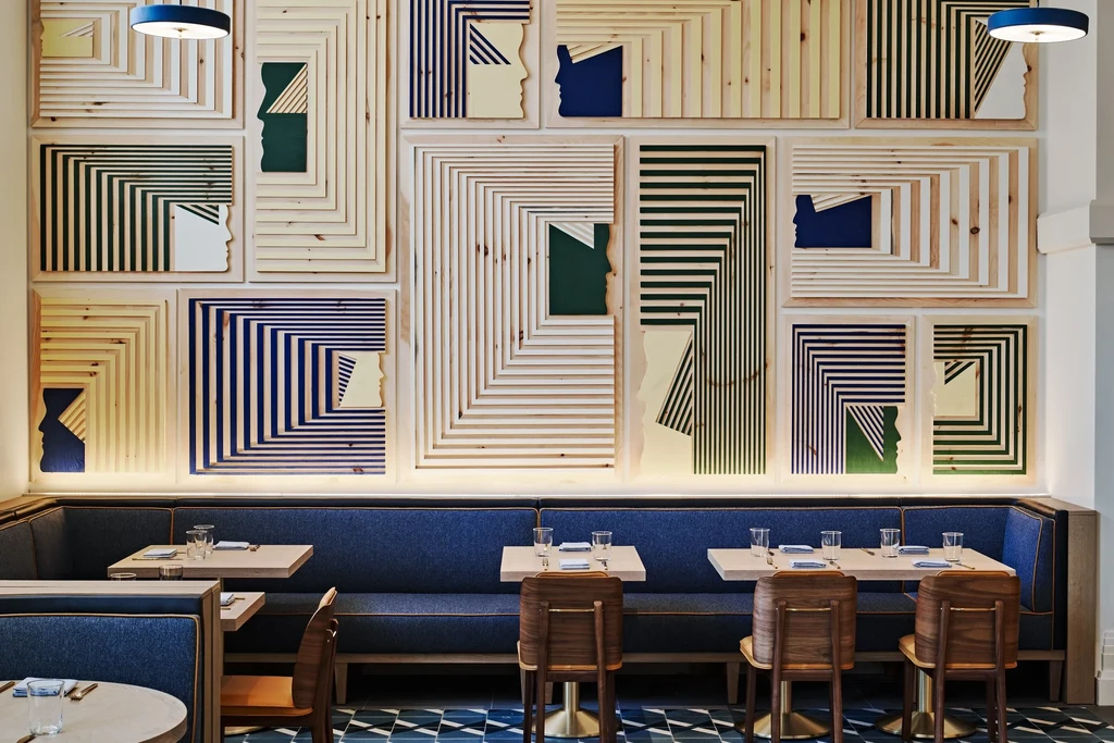 Restaurant interior with geometric wood panel wall art and blue booths.
