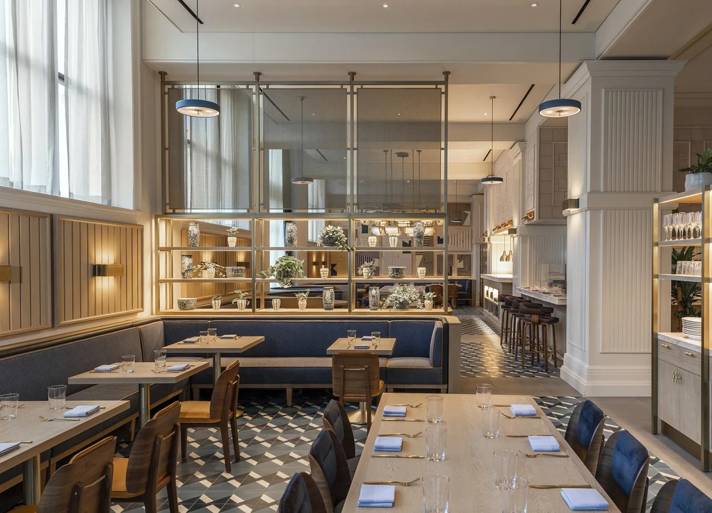 Empty modern restaurant interior with geometric floor, dining tables, and bar.