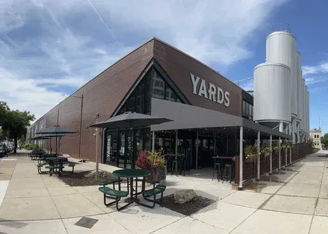 YARDS brewery building, patio with tables, and brewing tanks.