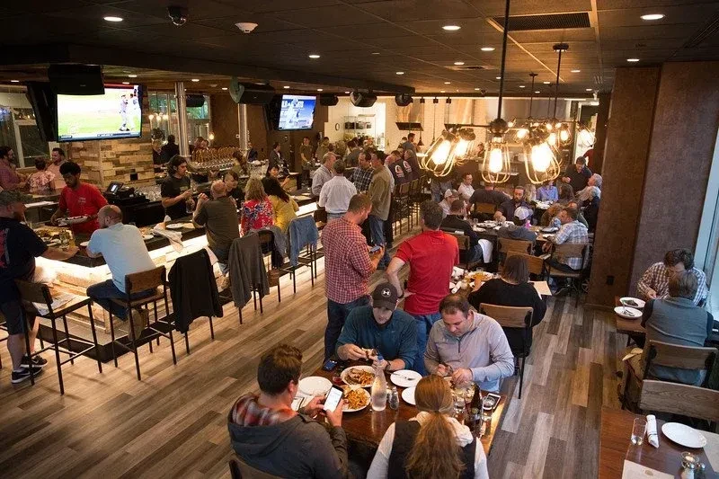 Busy modern restaurant interior featuring a bustling bar and dining area.