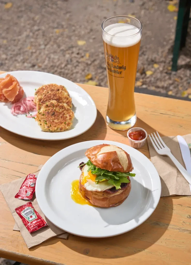 Outdoor dining: Pretzel bun sandwich, golden patties, beer, salmon.