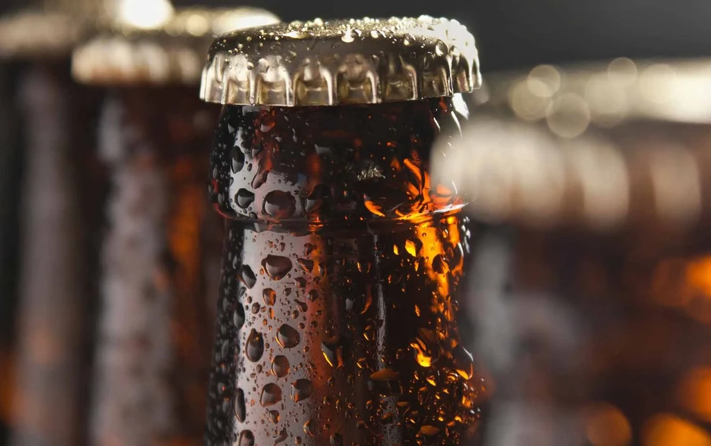 Amber glass bottle neck and cap covered in condensation droplets.