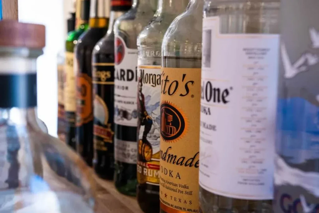 Labeled liquor bottles, including Ketel One and Bacardi, on a bar shelf.