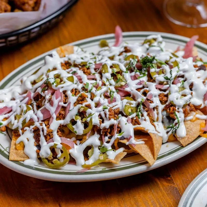 Top-down, close-up of fully loaded nachos with meat, cheese, and jalapeños.