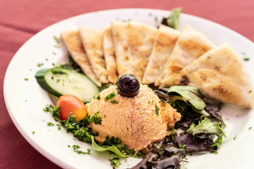 Hummus with olive and herbs, served with pita and fresh vegetables.