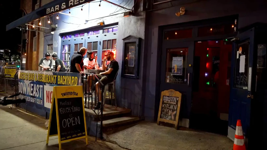 Night view of Kosta's bar and restaurant with people dining outside.