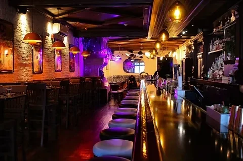 Trendy bar interior with long counter, brick wall, and atmospheric lighting.