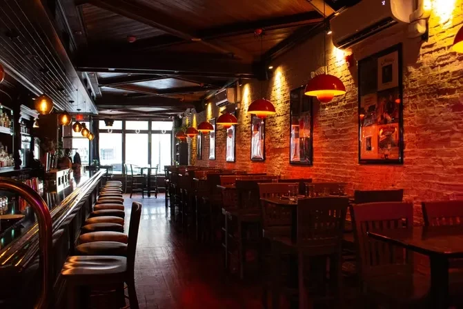 Warm, dimly lit restaurant interior with a bar and exposed brick.