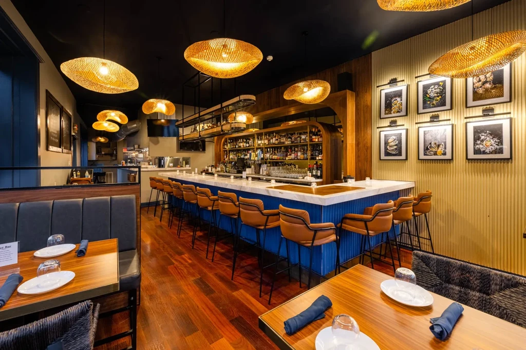 Modern upscale bar with blue base, marble counter, and woven lights.