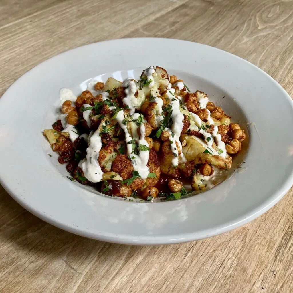 Roasted cauliflower and chickpeas with creamy sauce and fresh herbs.