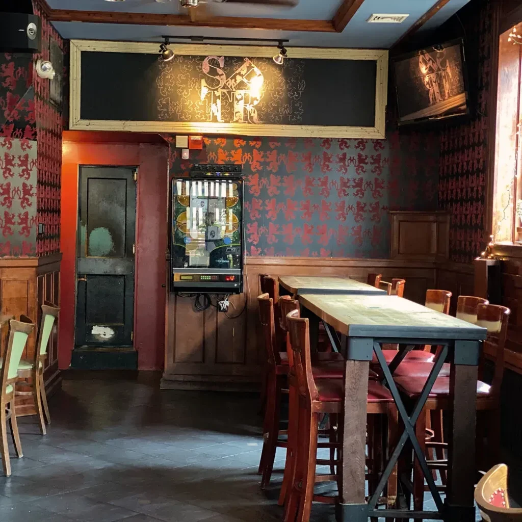 Empty bar interior with jukebox, chalkboard, and communal tables.