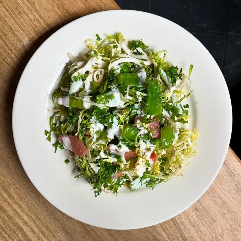 Overhead colorful salad with greens, pink grapefruit, and creamy dressing.
