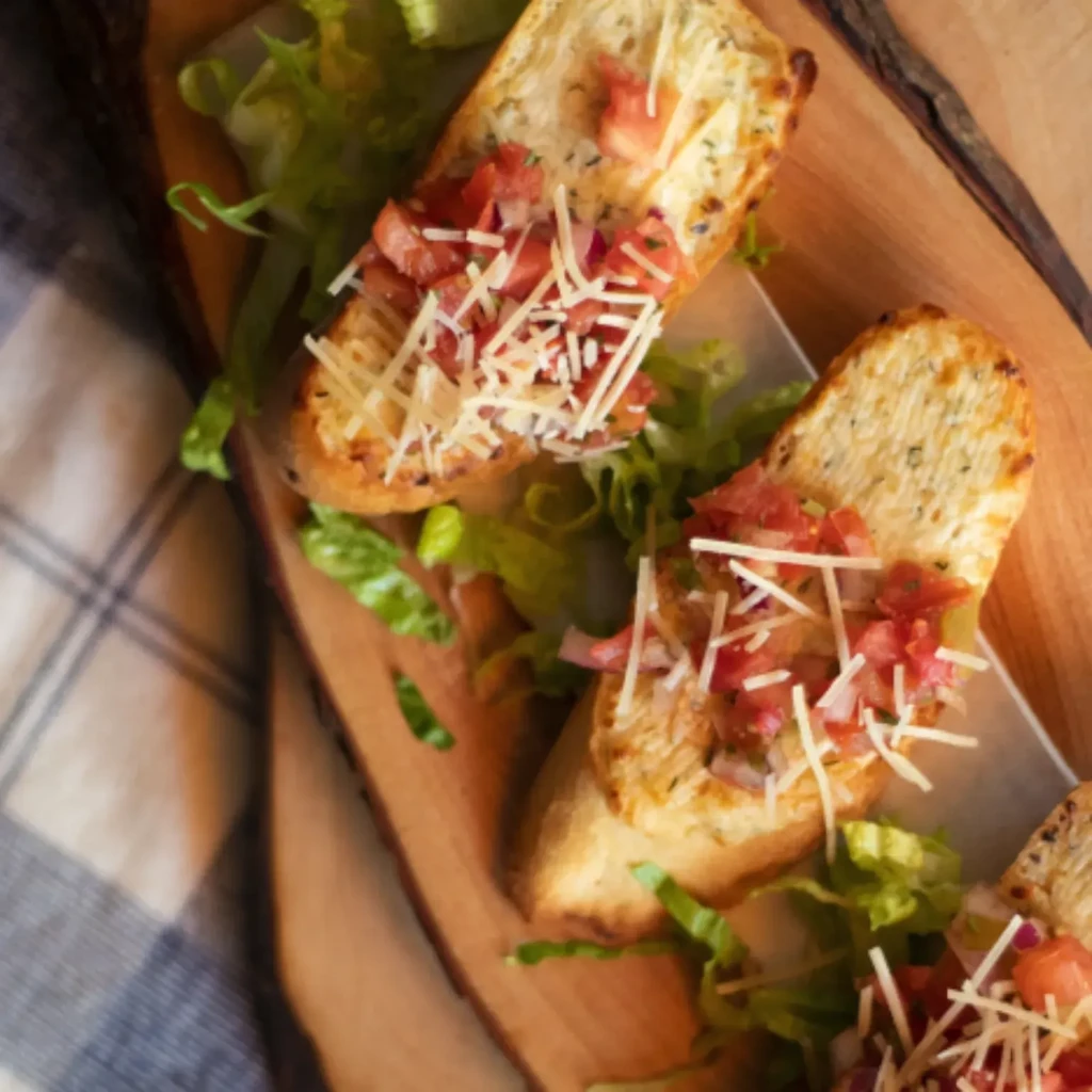 Bruschetta with tomatoes, onion, and Parmesan on a rustic wooden board.
