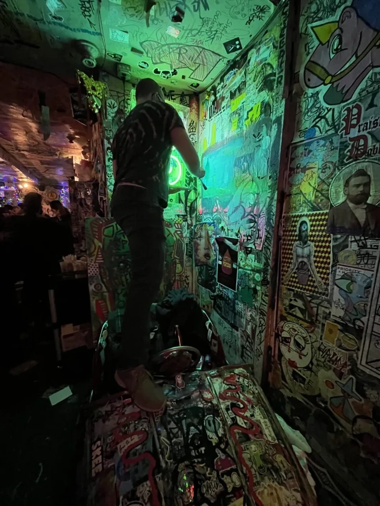Person on a counter in a room with green neon and graffiti.