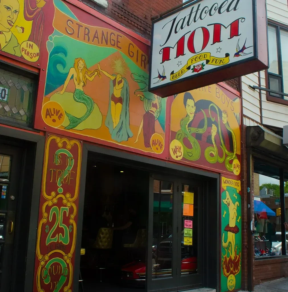 Colorful building exterior for "Tattooed MOM" with retro circus murals.
