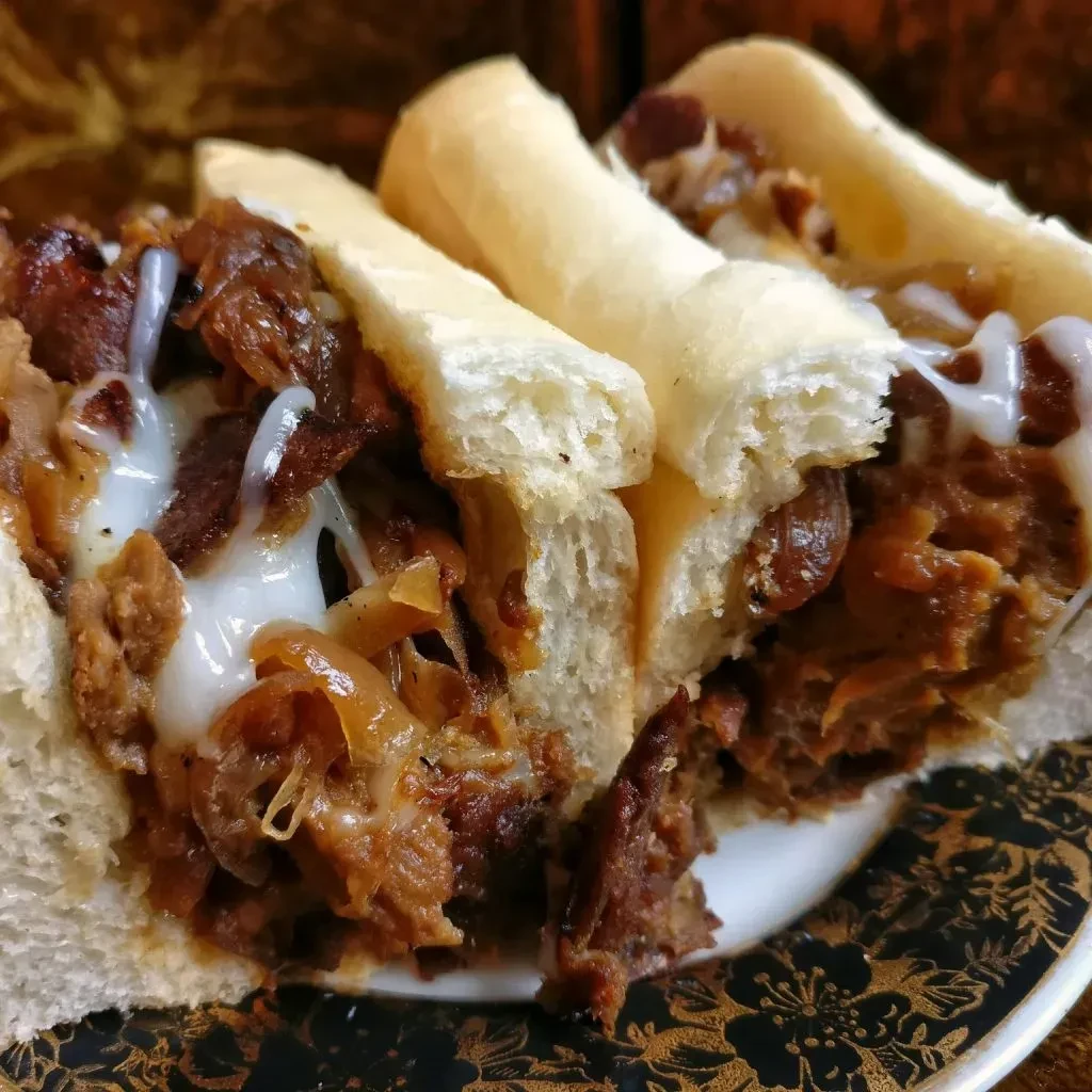 Three cheesesteak sandwiches with beef, onions, and melted cheese.