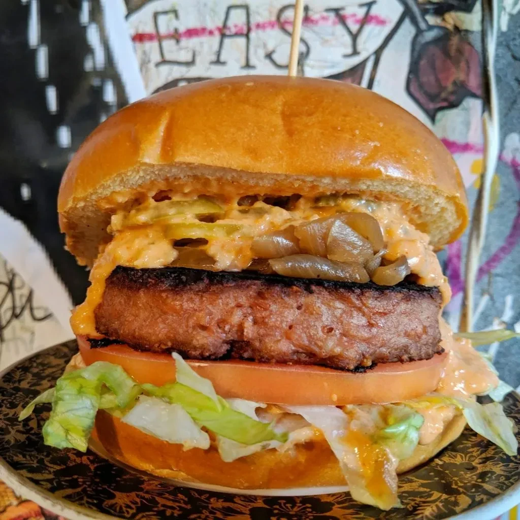 Char-grilled burger with orange sauce, jalapeños, tomato, and lettuce.