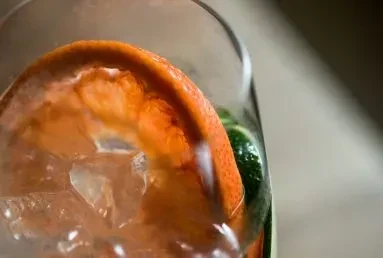 Close-up of a drink with grapefruit, lime, and ice in a glass.