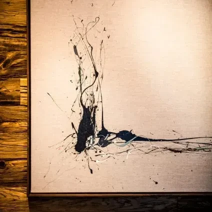 L-shaped abstract painting with dark blue and black paint on beige canvas.