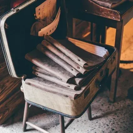 Vintage suitcase on stool displays aged menus and a Barcelona card.