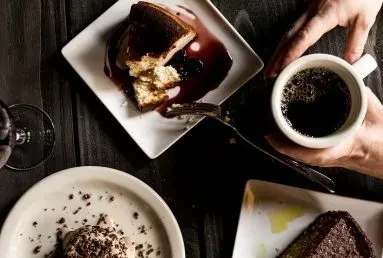 Overhead, rustic table filled with various desserts, coffee, and wine.