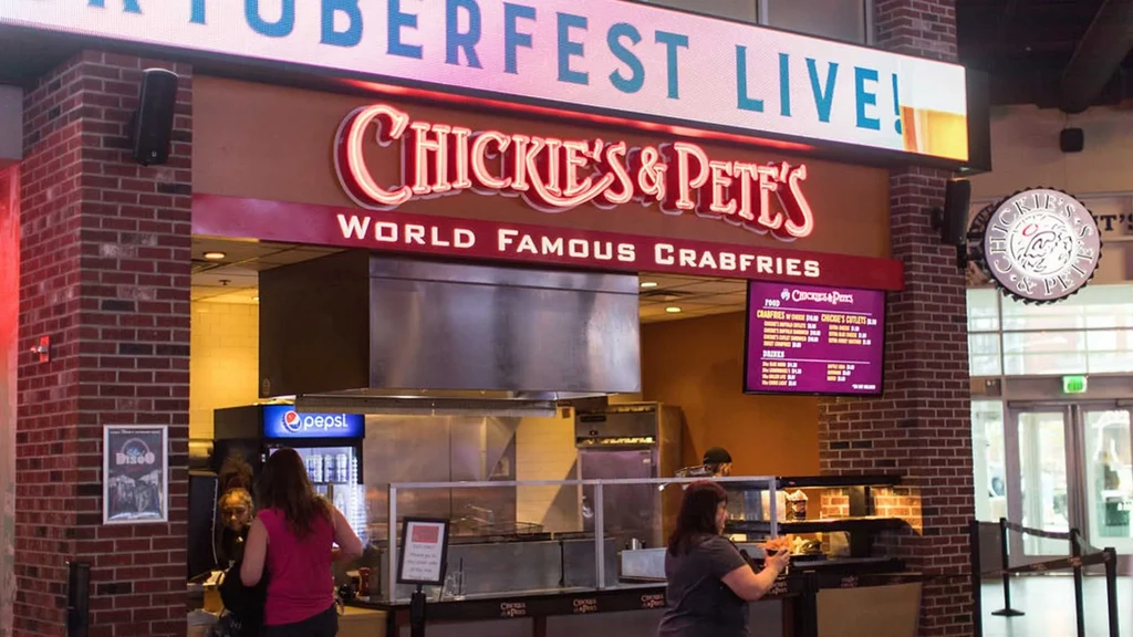Chickie's & Pete's counter with neon sign, 'Oktoberfest Live!' display, and customers.