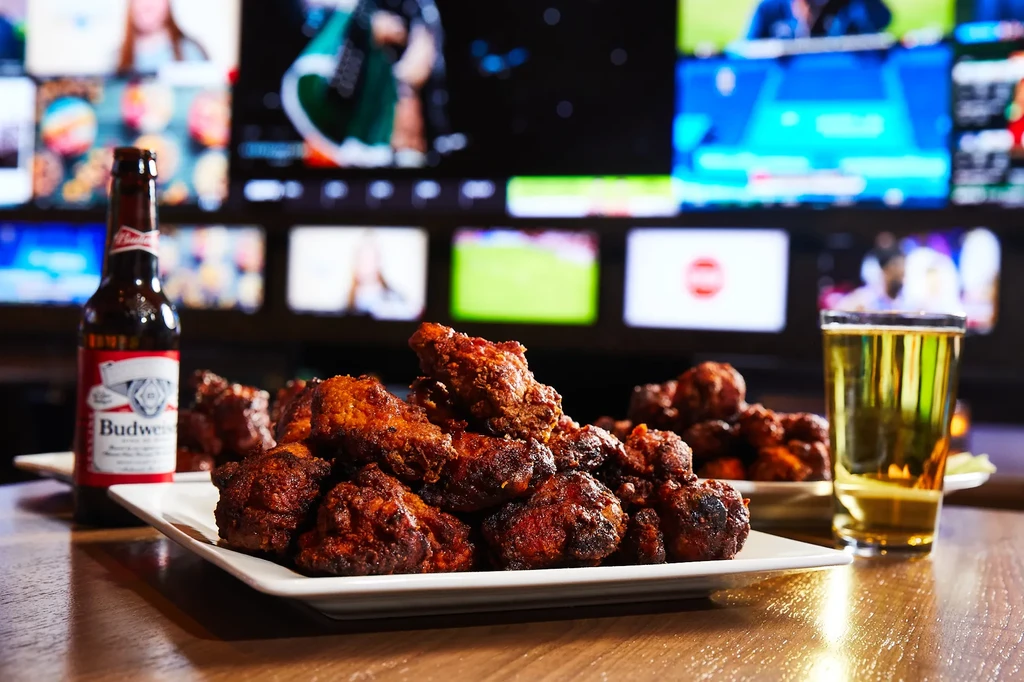 Crispy chicken wings, Budweiser beer, and a drink at a sports bar.