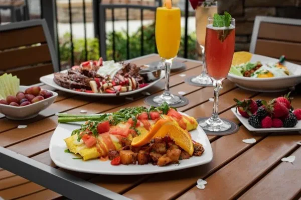 Outdoor brunch spread: omelet, chocolate pancakes, fresh fruit, and drinks.