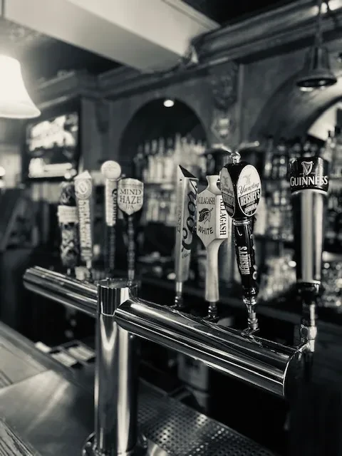 Five black and white beer tap handles, including Guinness and Allagash.