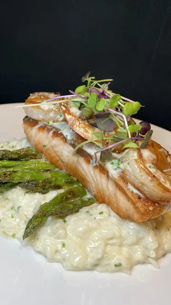 Grilled fish, shrimp, creamy sauce, risotto, asparagus, and microgreens.