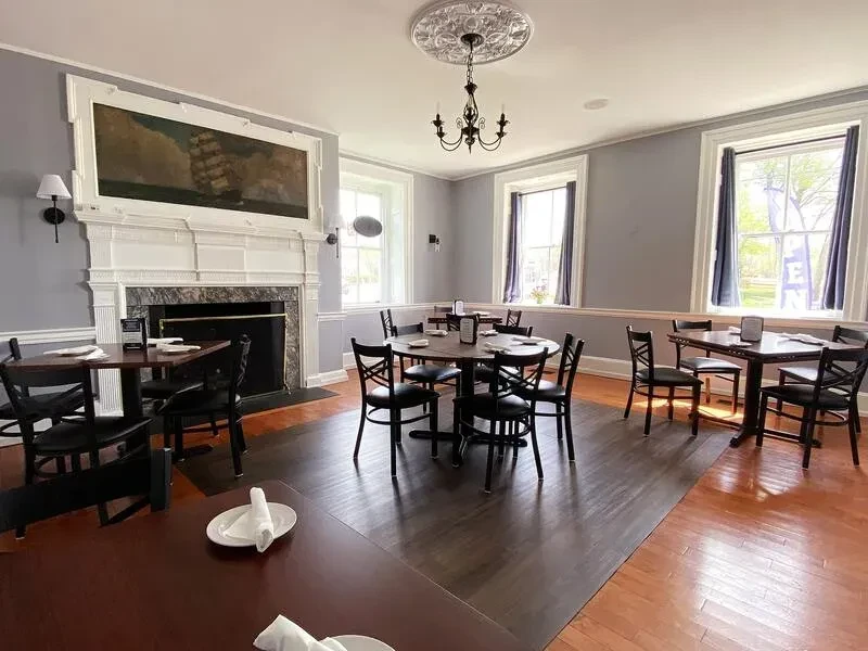 Classic restaurant dining room with fireplace, chandelier, and set tables.