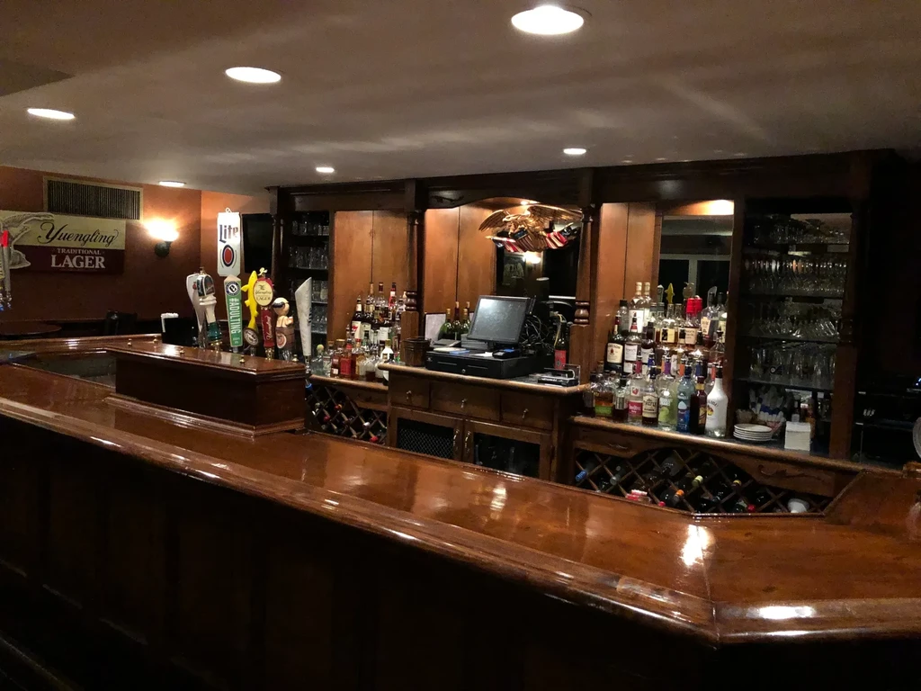 Warmly lit, well-stocked bar with liquor bottles and prominent beer taps.