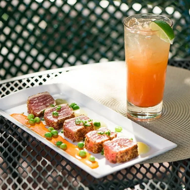 Seared tuna, green peas, sauces, and two-toned cocktail on patio.