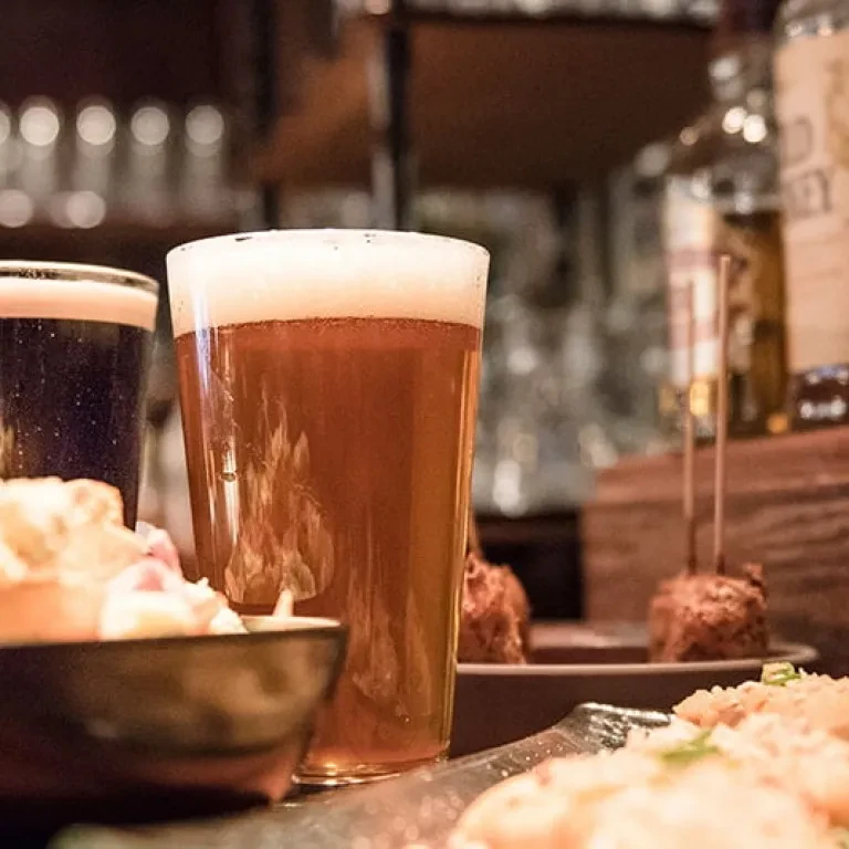 Close-up of an amber beer with food in a bar.