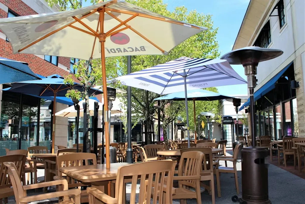 Empty outdoor patio with tables, chairs, Bacardi/Peroni umbrellas, and heaters.
