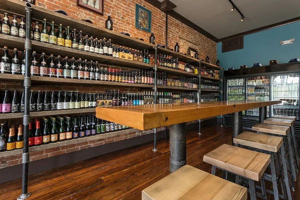 Industrial-style bar with wooden counter and shelves of bottled drinks.