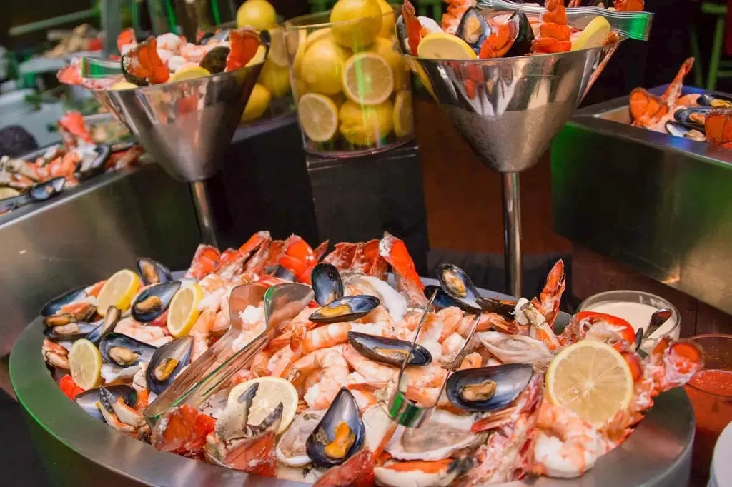 Large seafood buffet with shrimp, mussels, lobster, and lemons on ice.