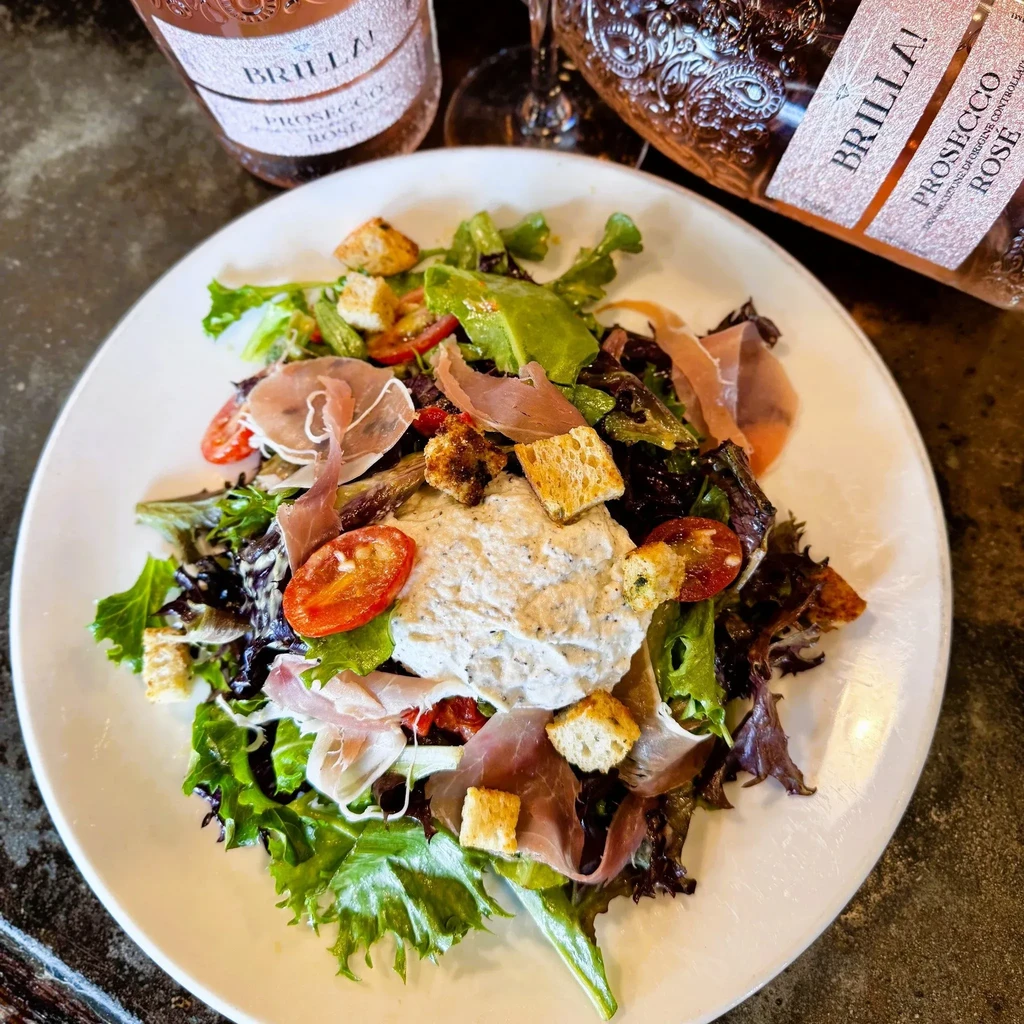 Salad with prosciutto and burrata, Brilla Prosecco Rosé bottles in background.