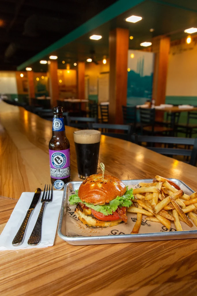 Gourmet burger, fries, bottled and dark beer served in a restaurant.