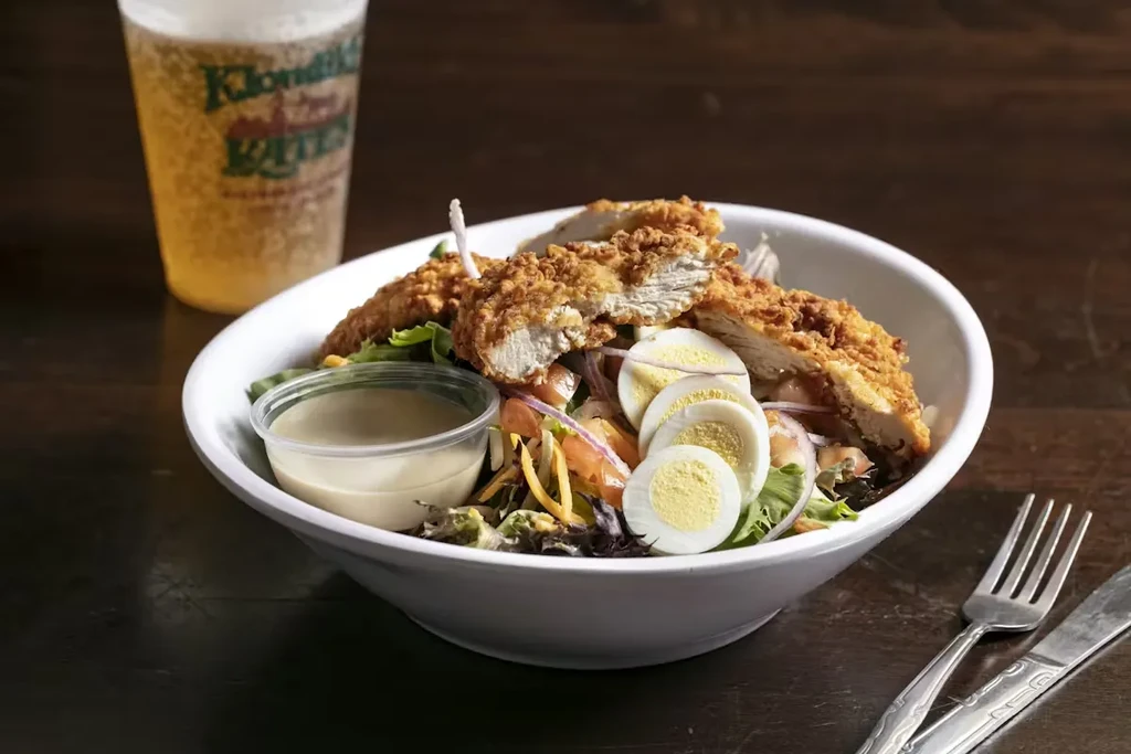 Hearty fried chicken salad with eggs, tomatoes, red onions, and beer.