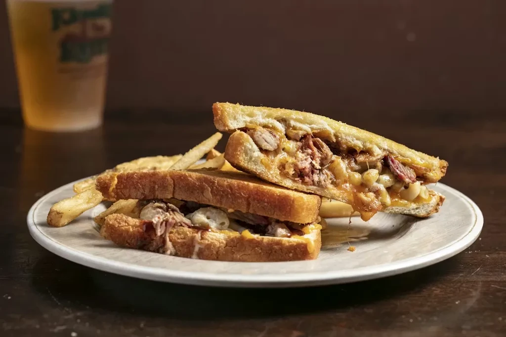 Grilled sandwich with melted cheese, golden fries on rustic plate.