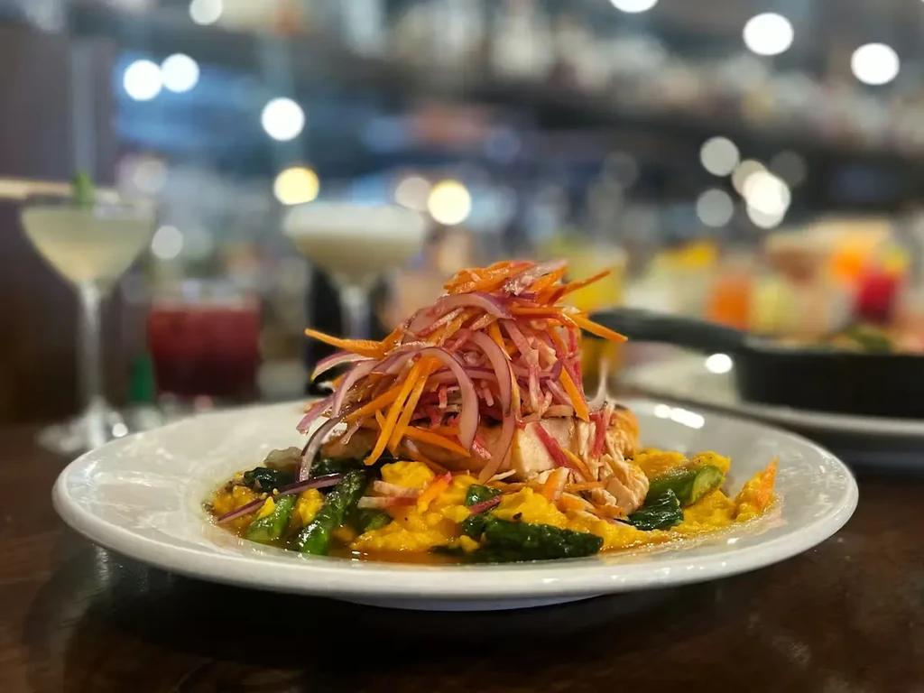 Close-up of a plated dish featuring meat, vegetables, and colorful slaw.