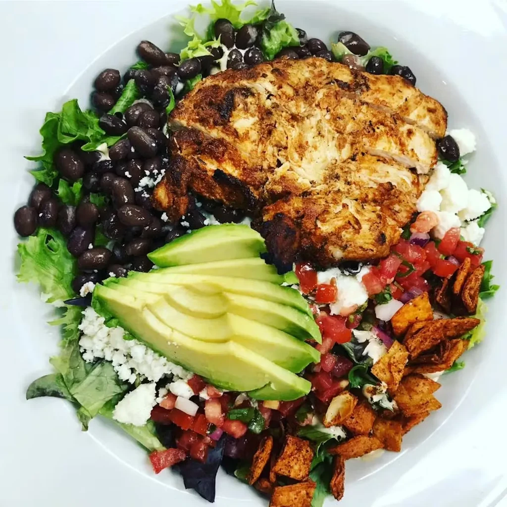 Sliced chicken, lettuce, black beans, avocado, cheese, salsa, tortilla strips.