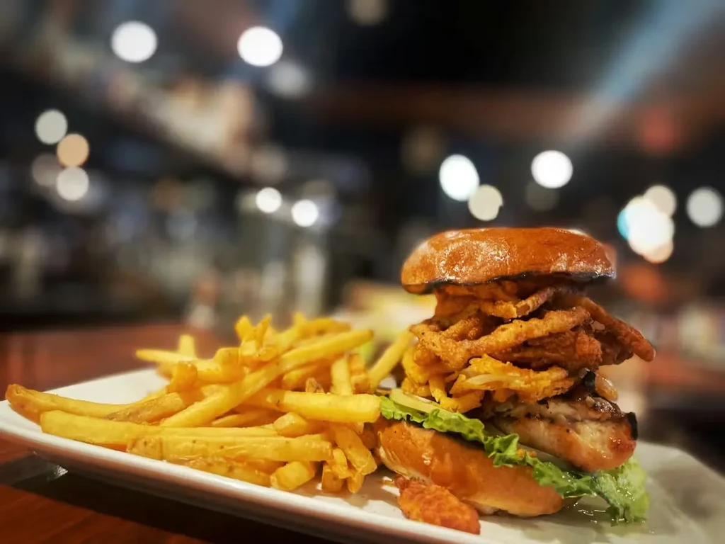 Grilled chicken burger with crispy fried onions and french fries.