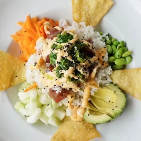 Overhead, colorful poke bowl with tuna, rice, and fresh vegetables.