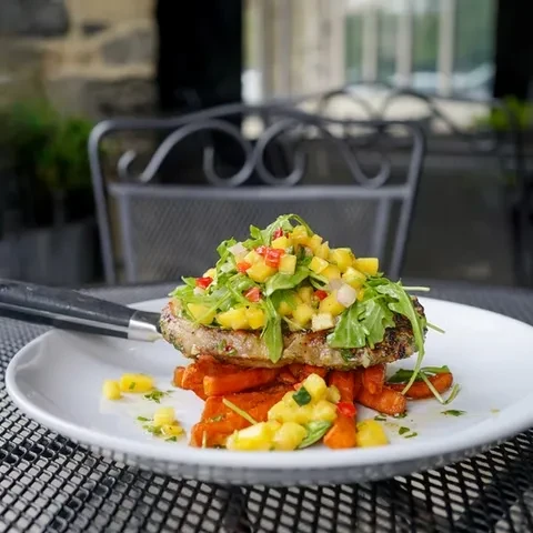 Grilled meat with mango salsa and sweet potato fries outdoors.