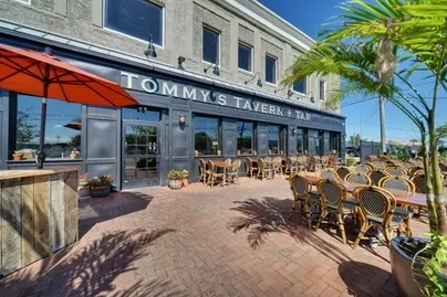 Tommy's Tavern + Tap: industrial-chic restaurant exterior with empty patio seating.